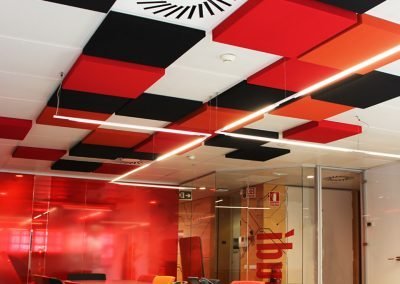 Paneles acústicos a techo de colores y cuadrados en una sala de reuniones
